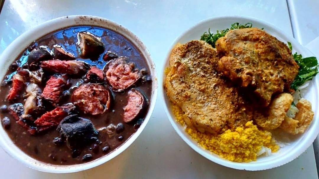 Feijoada com linguiça ao lado de bife empanado, farofa e arroz